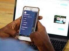 5 Ways to Convert Your Social Media Followers Into Customers Man looking at smartphone with laptop in background